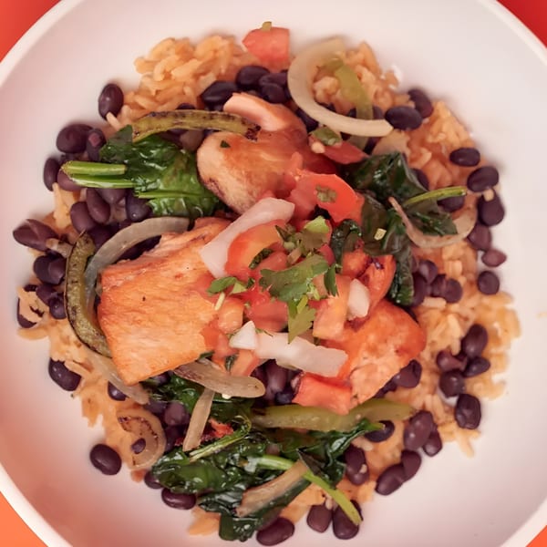 A vibrant Mexican bowl with chicken, rice, black beans, spinach, and fresh salsa.