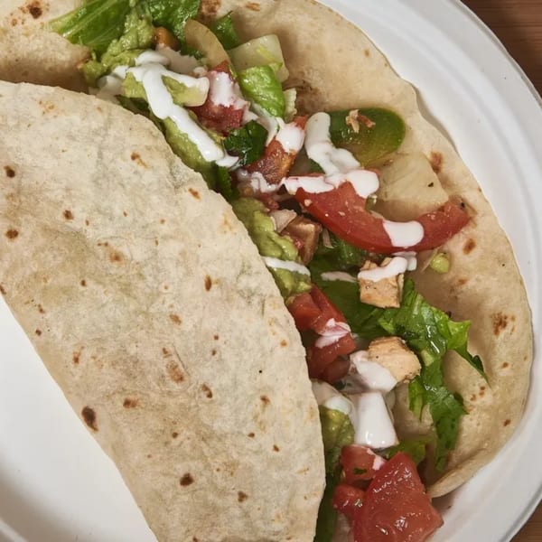 A 360 Gourmet Burrito filled with chicken, lettuce, tomatoes, guacamole, and sour cream.