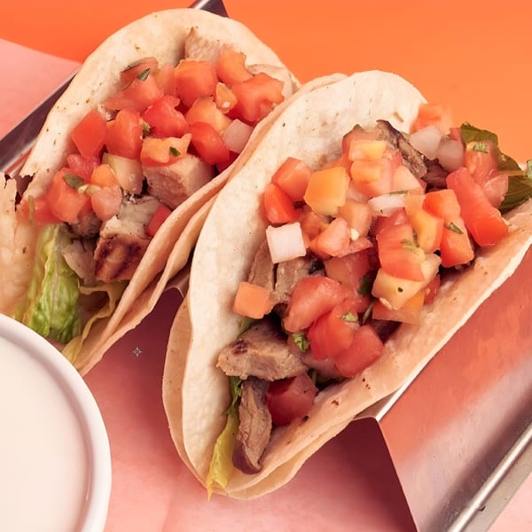 Two 360 Gourmet Burritos tacos with meat, lettuce, and diced tomatoes, onions, and cilantro.